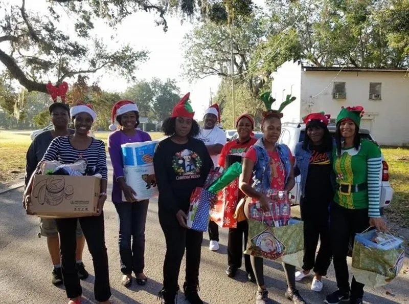 Ministry volunteers in Christmas hats holding gifts for a community giveaway