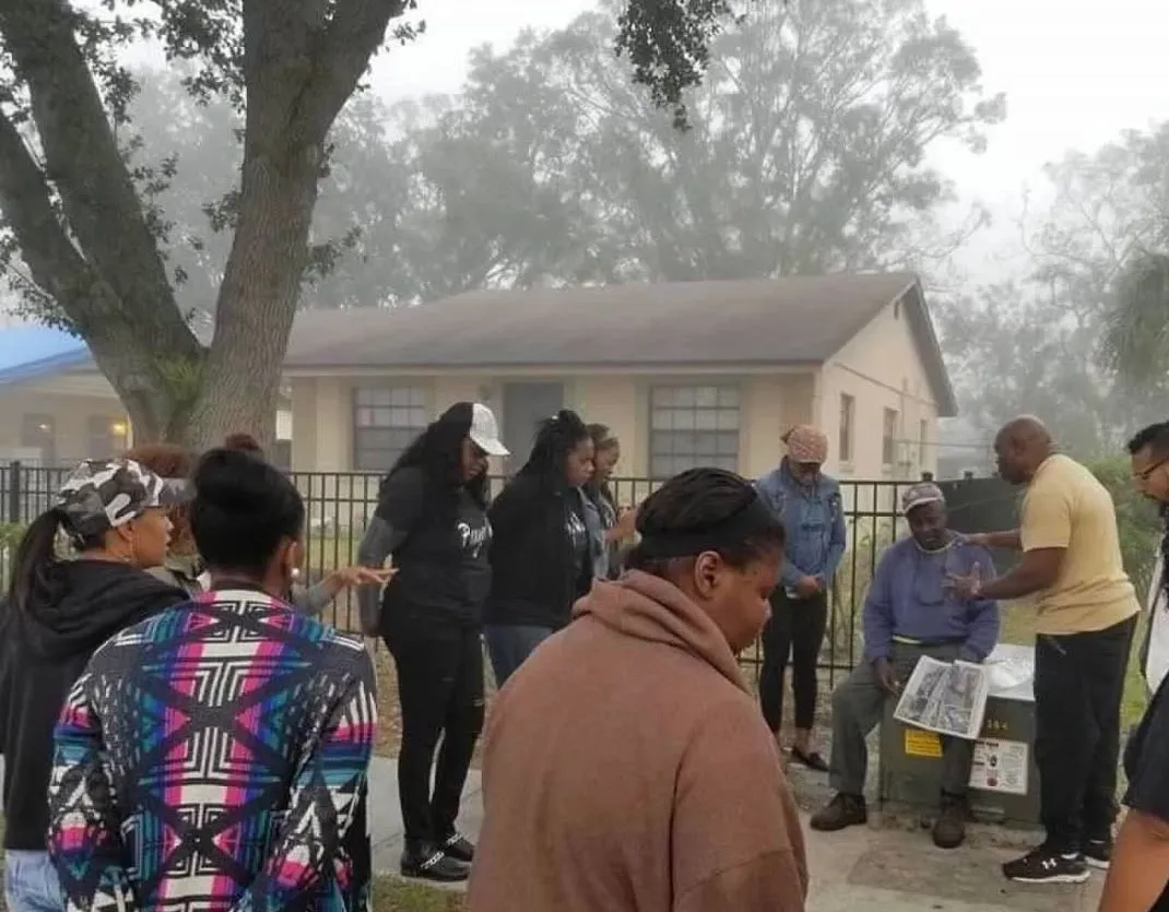 Ministry members praying with neighbors outdoors on a misty morning