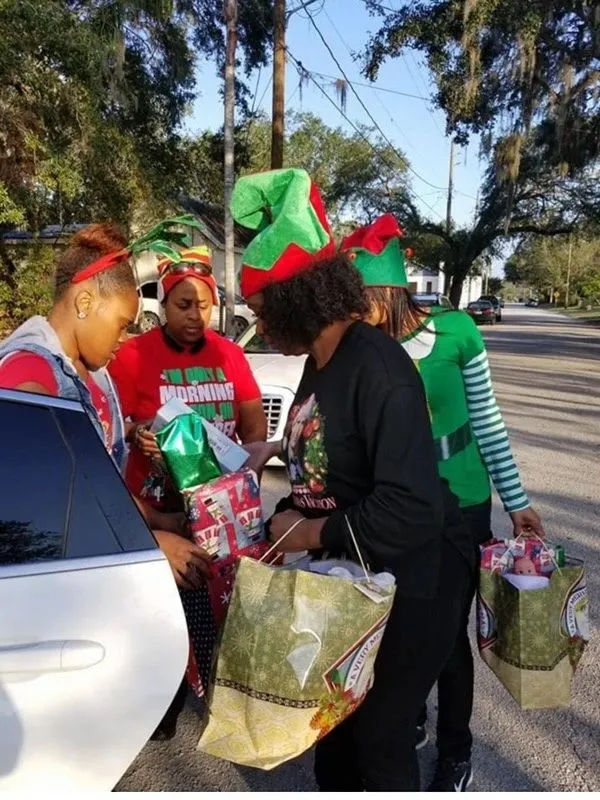 Volunteers in elf hats handing out gift bags from a car